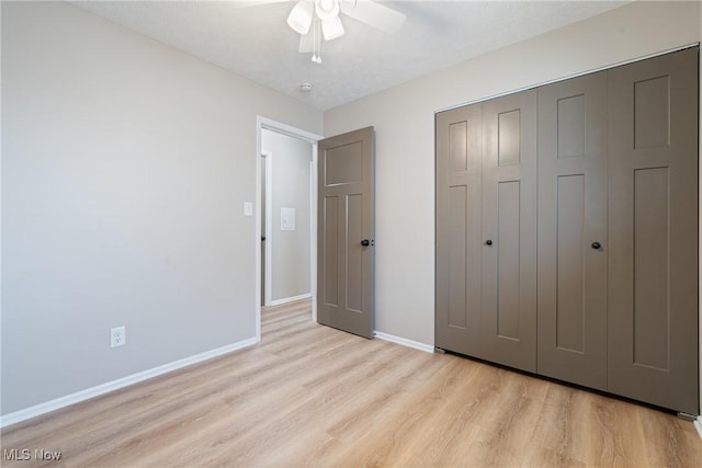 unfurnished bedroom featuring light wood-style floors, a ceiling fan, baseboards, and a closet