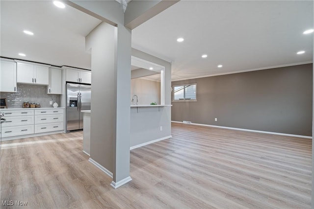 kitchen featuring white cabinets, decorative backsplash, light countertops, light wood-type flooring, and stainless steel refrigerator with ice dispenser