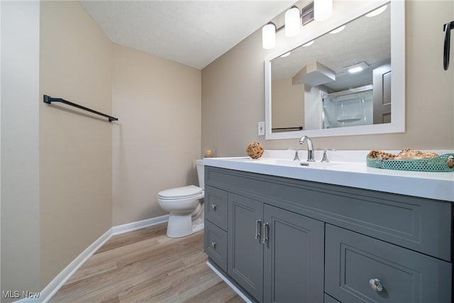 full bath featuring toilet, baseboards, wood finished floors, and vanity