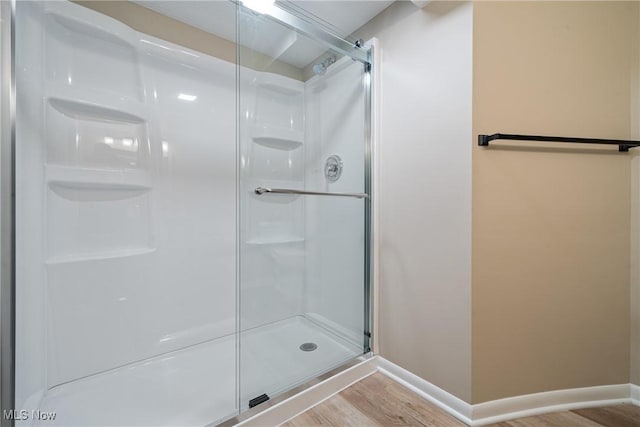 full bath featuring a stall shower, baseboards, and wood finished floors