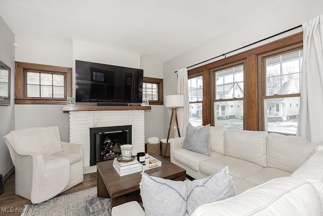 living area with a brick fireplace and wood finished floors