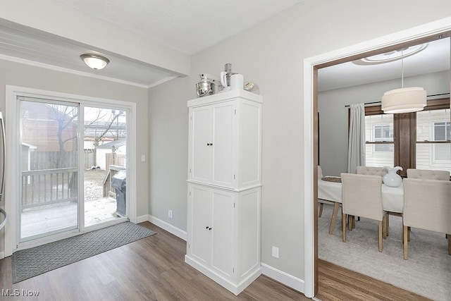 doorway to outside featuring baseboards and wood finished floors