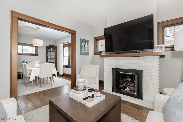 living area featuring a brick fireplace, wood finished floors, and baseboards