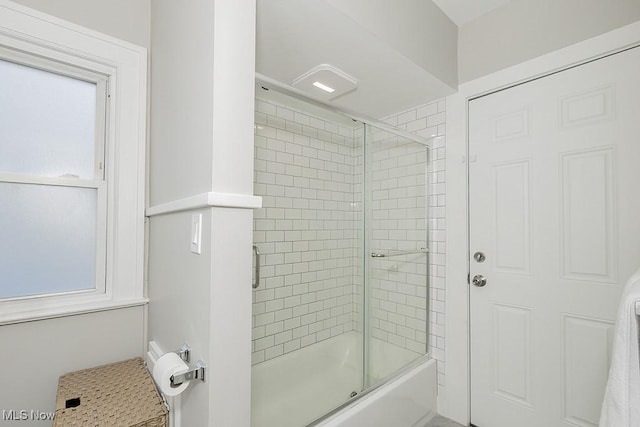 bathroom featuring plenty of natural light and bath / shower combo with glass door