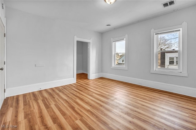 empty room featuring light wood finished floors, visible vents, and baseboards