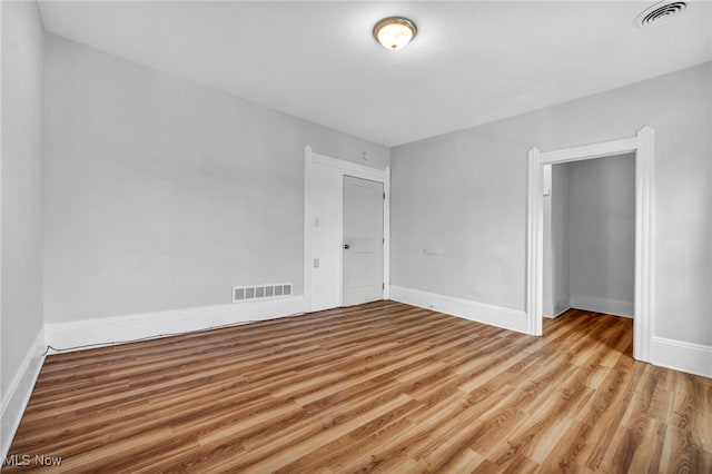 unfurnished bedroom featuring visible vents, baseboards, and wood finished floors