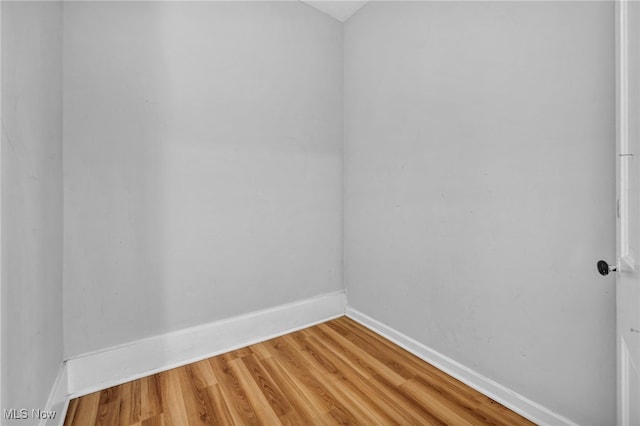 spare room with baseboards and wood finished floors