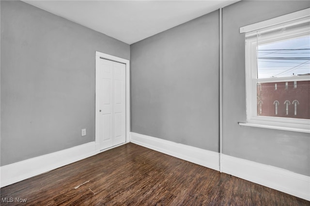 empty room with baseboards and dark wood finished floors