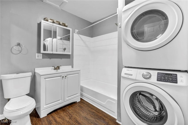 clothes washing area featuring laundry area, dark wood-type flooring, stacked washer and dryer, and a sink