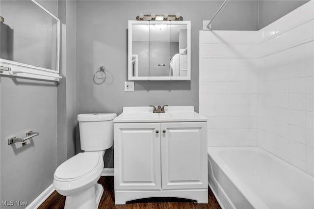 full bathroom with toilet, washtub / shower combination, vanity, wood finished floors, and baseboards