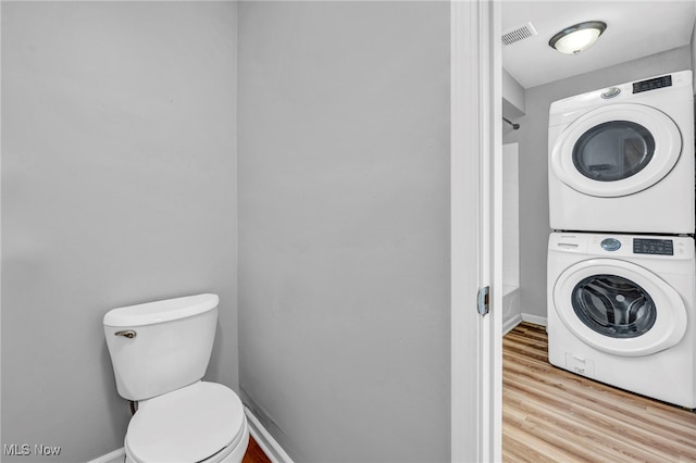 interior space featuring stacked washer / drying machine, visible vents, wood finished floors, laundry area, and baseboards