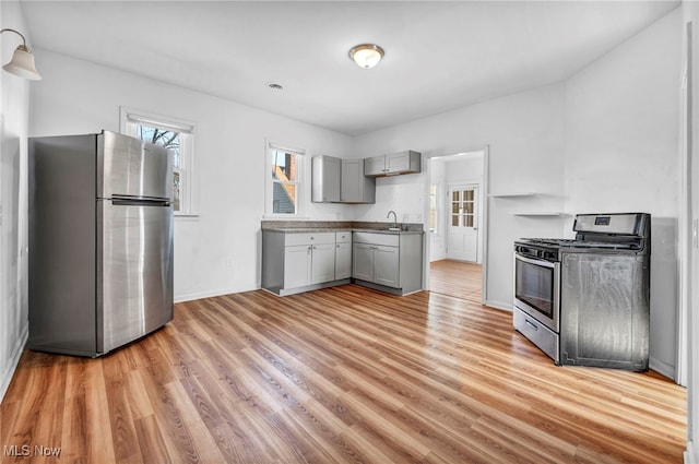 kitchen with light wood-style flooring, appliances with stainless steel finishes, gray cabinets, and baseboards