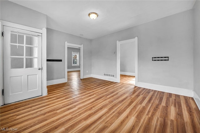 unfurnished room featuring baseboards, visible vents, and wood finished floors