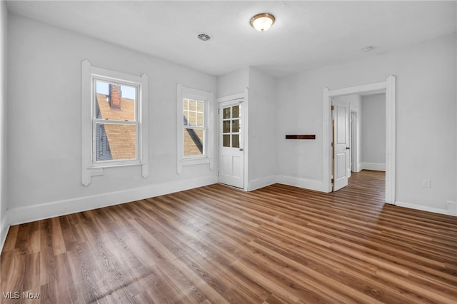 spare room featuring baseboards and wood finished floors