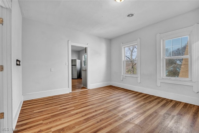 spare room with baseboards, visible vents, and light wood finished floors