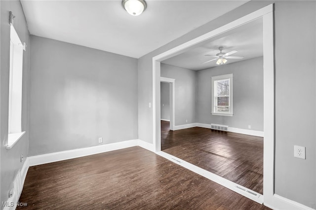 empty room with visible vents, ceiling fan, baseboards, and wood finished floors