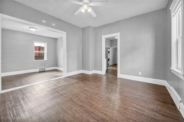 unfurnished room with ceiling fan, dark wood-type flooring, visible vents, and baseboards