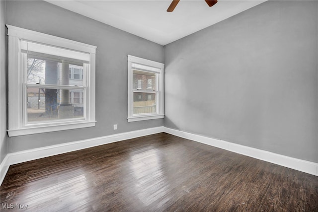 empty room with baseboards, dark wood finished floors, and a ceiling fan