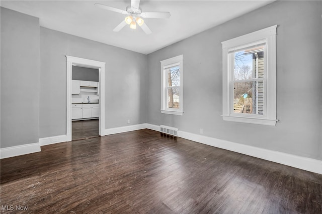 unfurnished bedroom with dark wood-type flooring, visible vents, baseboards, and multiple windows