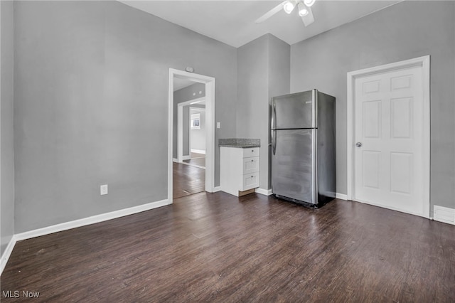 kitchen with baseboards, dark wood-style flooring, freestanding refrigerator, and white cabinetry