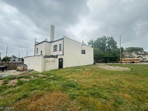 view of property exterior featuring a lawn, fence, and stucco siding