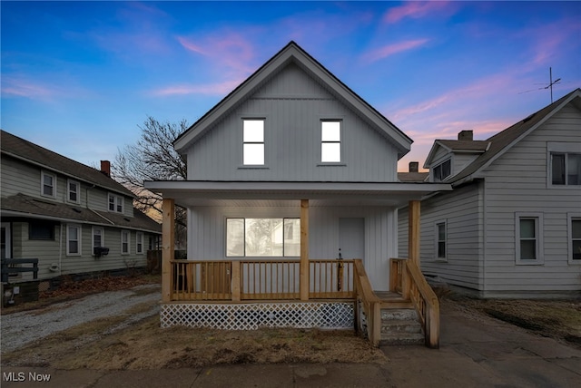 back of property at dusk with covered porch