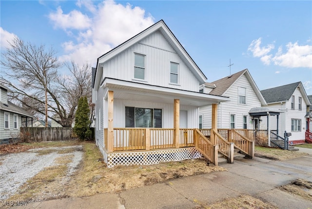 view of front of house featuring board and batten siding, covered porch, driveway, and fence