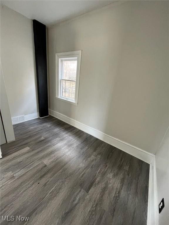 empty room with dark wood-type flooring and baseboards