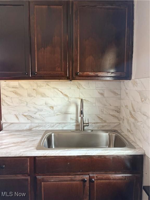 kitchen with backsplash, light countertops, and a sink