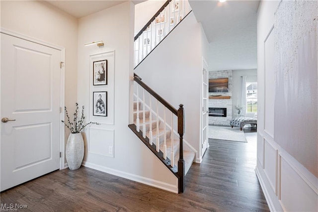 entrance foyer featuring stairs, a fireplace, and wood finished floors