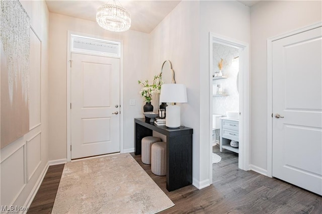 foyer featuring a chandelier, dark wood finished floors, and baseboards