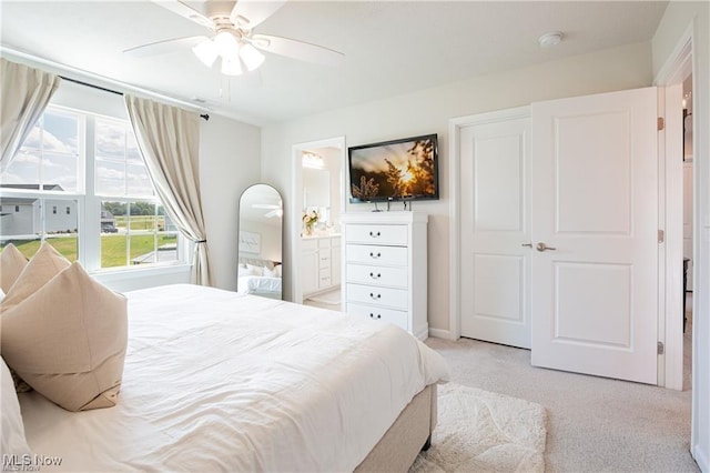 bedroom with light colored carpet, ceiling fan, and ensuite bath