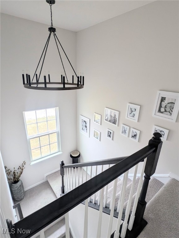 staircase featuring carpet floors, an inviting chandelier, and baseboards