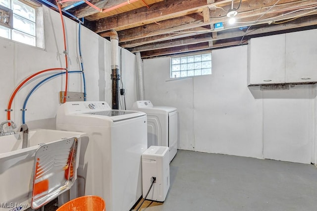 clothes washing area with laundry area, independent washer and dryer, a sink, and a wealth of natural light