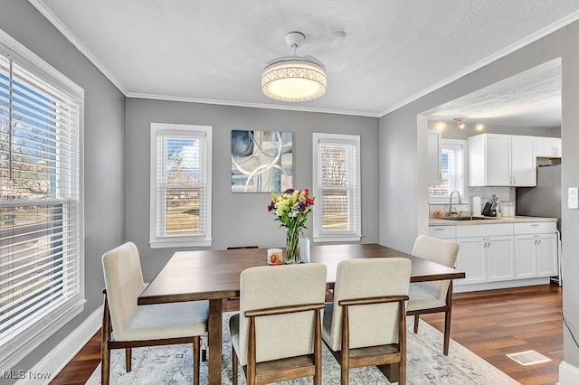 dining area with baseboards, dark wood-style flooring, visible vents, and crown molding