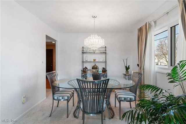 carpeted dining space featuring baseboards and an inviting chandelier