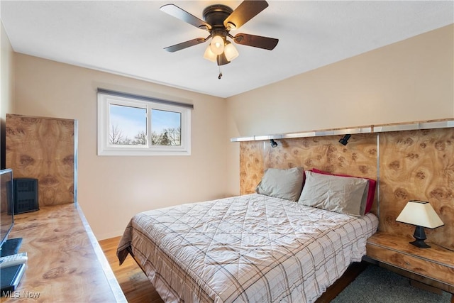 bedroom featuring wood finished floors, a ceiling fan, and baseboards