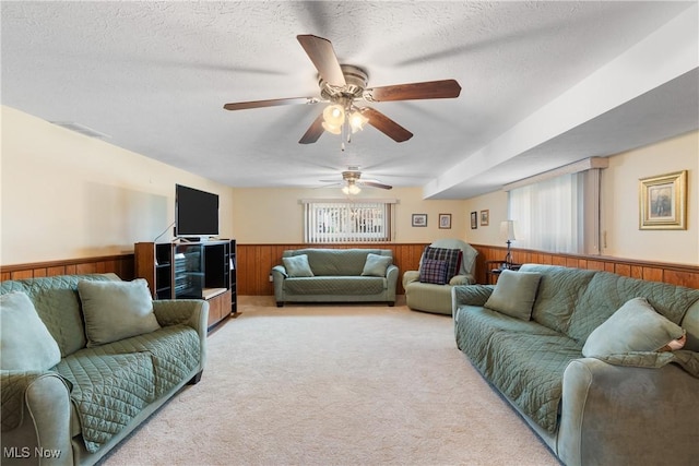 living room with wood walls, carpet, a textured ceiling, and wainscoting