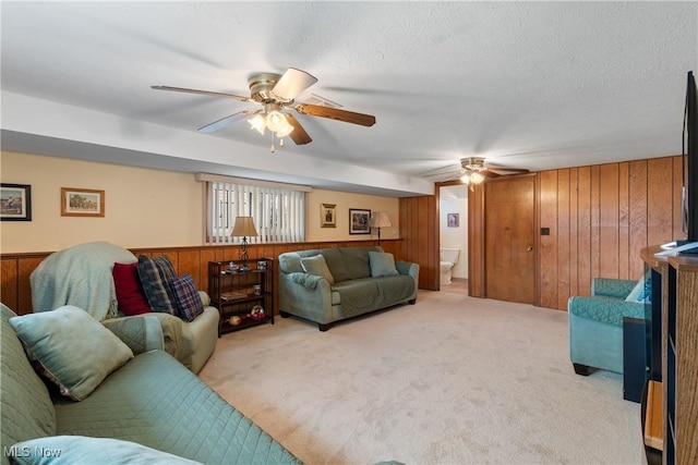 carpeted living room featuring wood walls, ceiling fan, and a textured ceiling