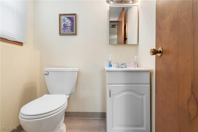 bathroom featuring toilet, baseboards, and vanity