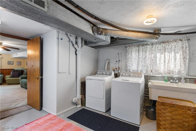 clothes washing area featuring washer and clothes dryer, a sink, ceiling fan, a textured ceiling, and laundry area