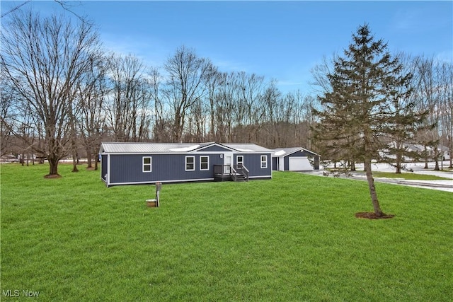 manufactured / mobile home with a garage, metal roof, an outbuilding, and a front yard