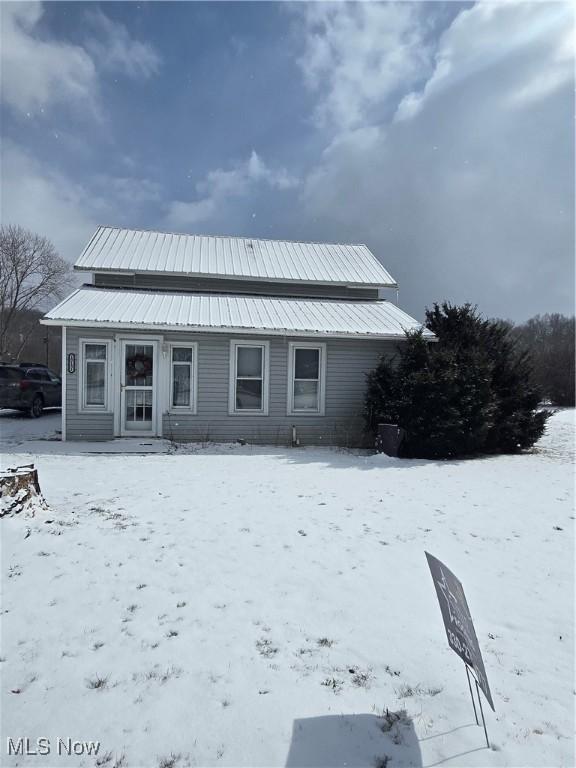 snow covered back of property featuring metal roof