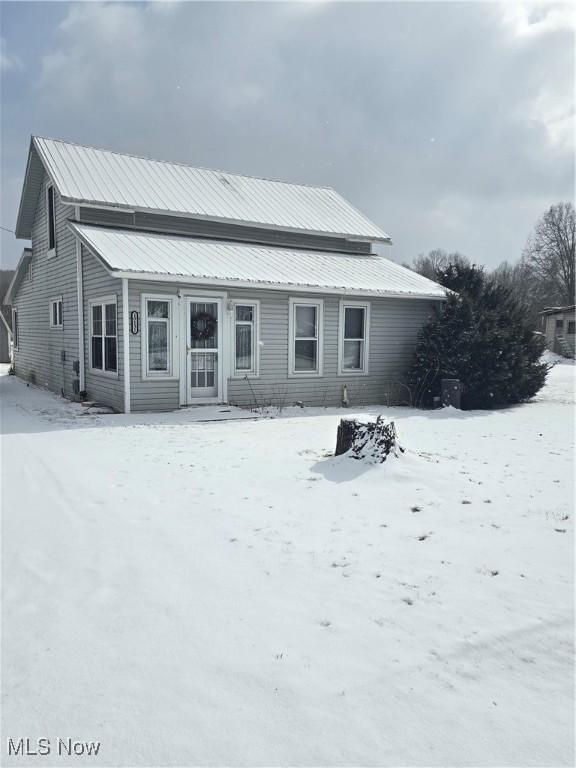 snow covered rear of property with metal roof