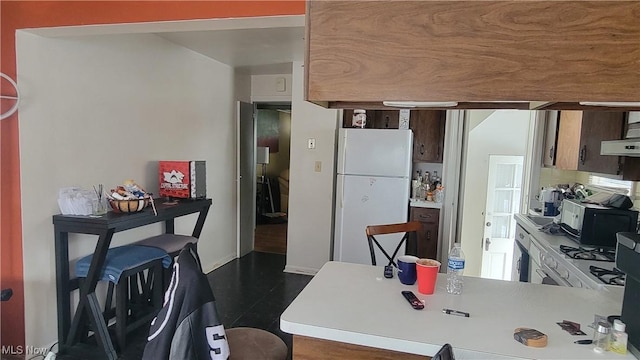 kitchen featuring freestanding refrigerator, light countertops, under cabinet range hood, and a peninsula