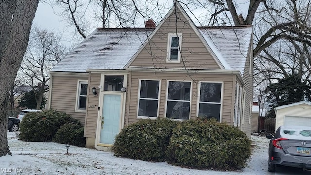 view of front of home featuring roof with shingles, a chimney, and an outdoor structure