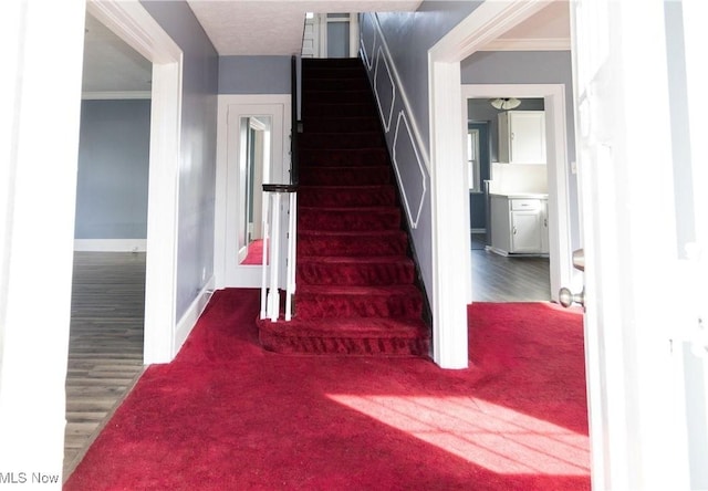 stairs featuring ornamental molding, wood finished floors, and baseboards