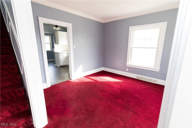 carpeted spare room with ornamental molding, visible vents, and baseboards