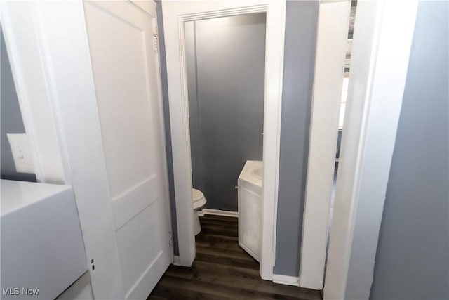 half bathroom with toilet, wood finished floors, and vanity