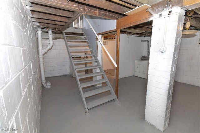 unfinished below grade area featuring stairway and washer / clothes dryer